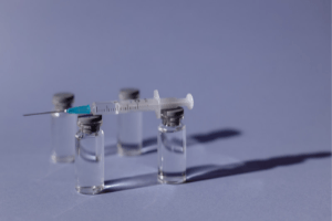 Vials of vaccine standing beside a syringe